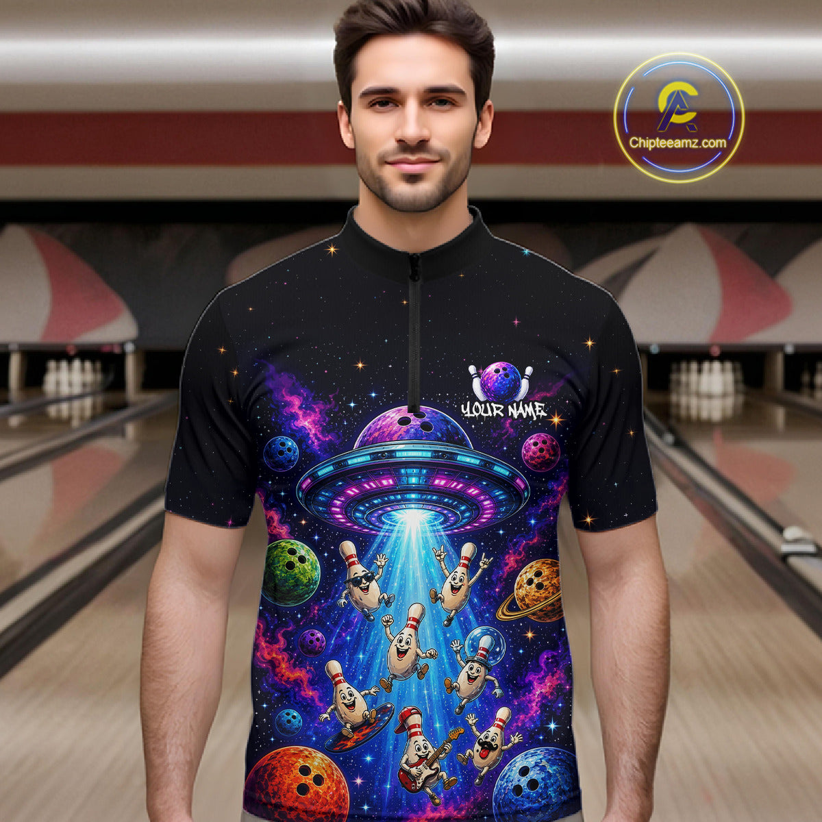 Man wearing a black t-shirt with a colorful alien abduction design in a bowling alley.