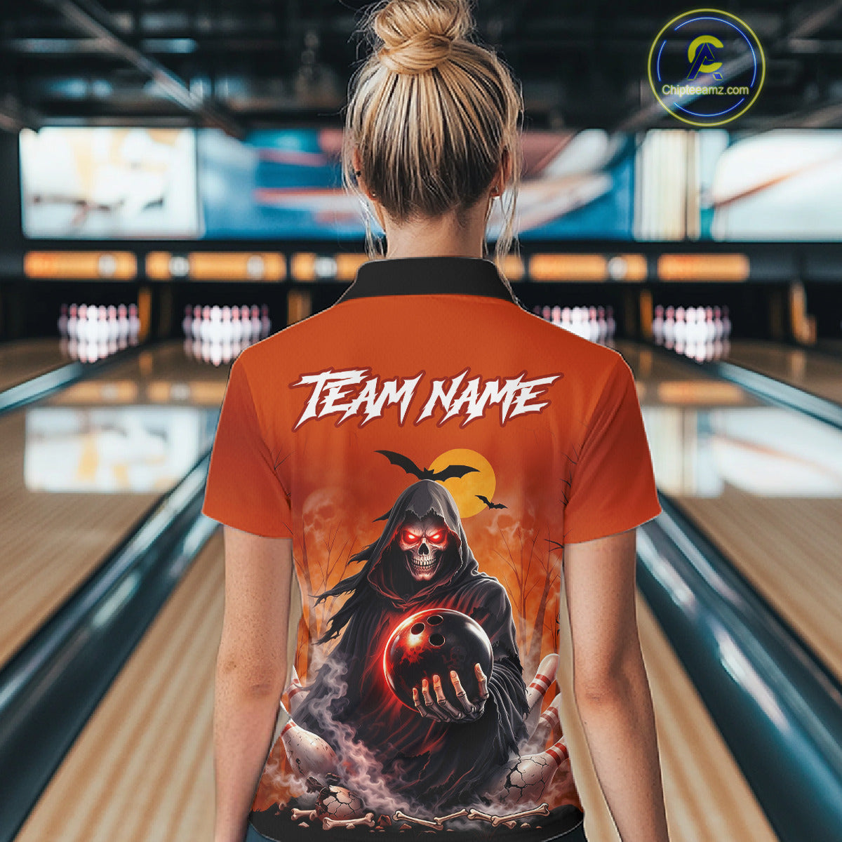 Female model wearing a custom orange grim reaper bowling polo shirt back view displaying the personalized team name above a hooded grim reaper artwork at the bowling alley