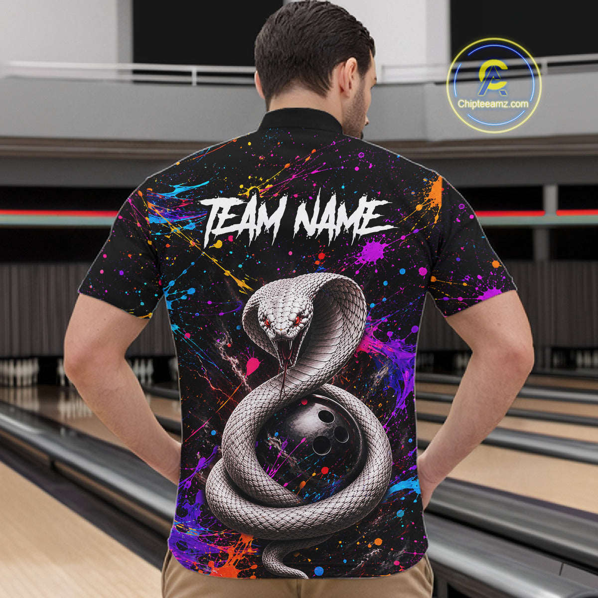 Person wearing a colorful bowling shirt with a snake design and 'TEAM NAME' text at a bowling alley.