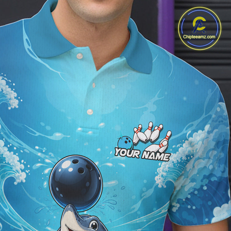 A close-up of a person wearing a bright blue short-sleeve polo shirt with a bowling-themed graphic print, including a bowling ball, pins, waves, and placeholder text reading 'YOUR NAME'. 