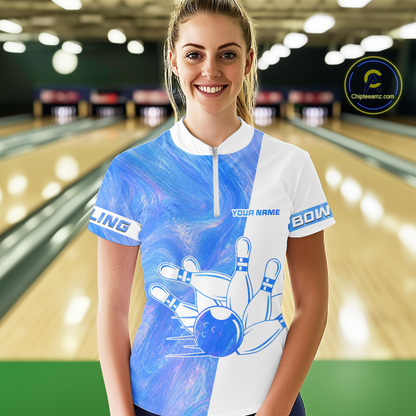 Woman wearing a blue and white bowling jersey with a bowling alley in the background