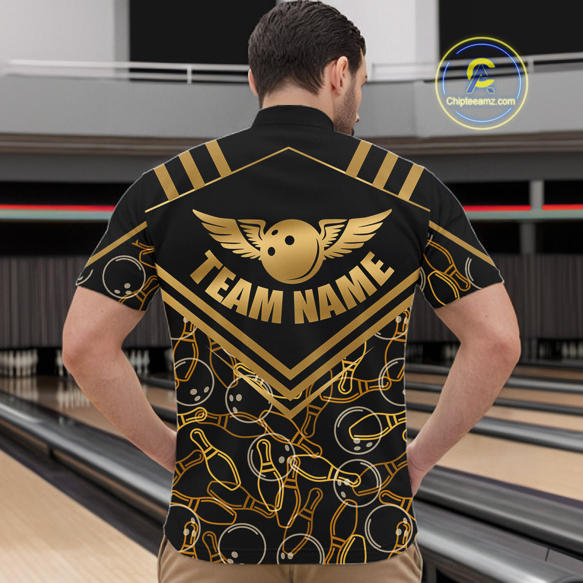 Male model wearing a custom black gold bowling quarter-zip shirt back view displaying the personalized team name above a golden winged bowling ball graphic at the bowling alley