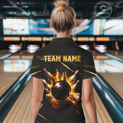 Woman wearing custom black gold bowling polo shirt back view featuring a fiery bowling ball and flame burst effect, displaying Team Name, at the bowling alley