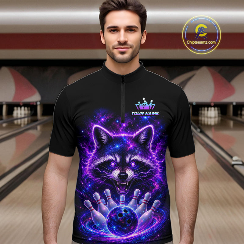 A man wearing a black short-sleeve zip-front bowling jersey with a large glowing raccoon graphic in purple, blue, and pink on the front, standing in a bowling alley. The shirt has a small crown logo and the text 'YOUR NAME' on the chest.