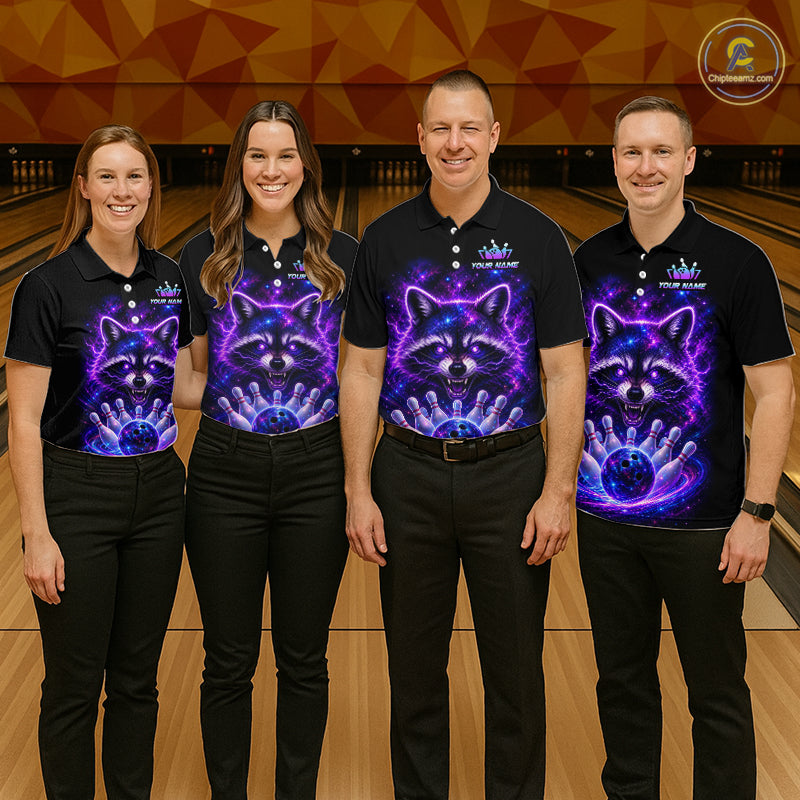 Four people standing in a bowling alley wearing matching black polo shirts with a vibrant purple and blue cosmic raccoon graphic on the front. The shirts also feature a small white logo on the left chest and a crown graphic on the right chest.