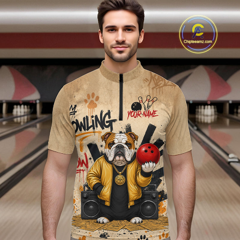 A man wearing a beige short-sleeve zip-front shirt with a bowling-themed graphic print featuring an bulldog in a yellow jacket holding a red bowling ball, set against a bowling alley background. A circular 'Chipeeamz.
