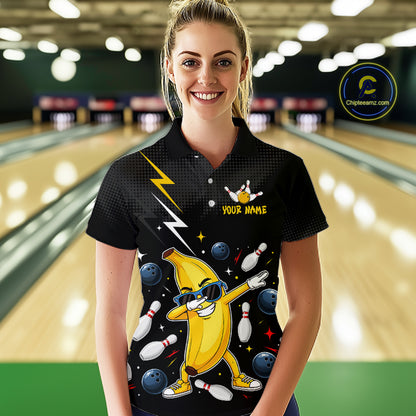 Person wearing a black bowling-themed shirt with a cartoon banana in a bowling alley.