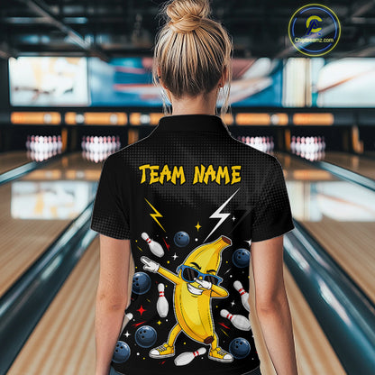 Person wearing a black bowling shirt with a banana character and 'Team Name' text in a bowling alley.