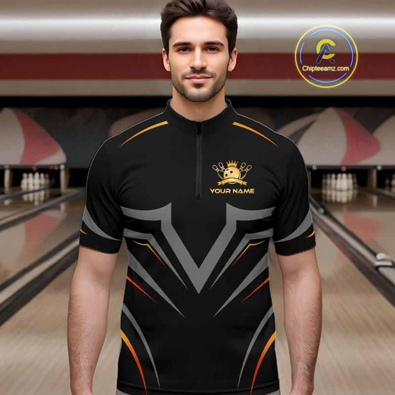 Man wearing a black bowling shirt with a logo and text in a bowling alley.