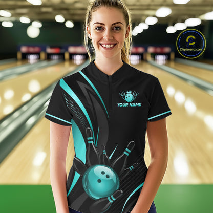 Person wearing a black and teal bowling shirt with a personalized design in a bowling alley.