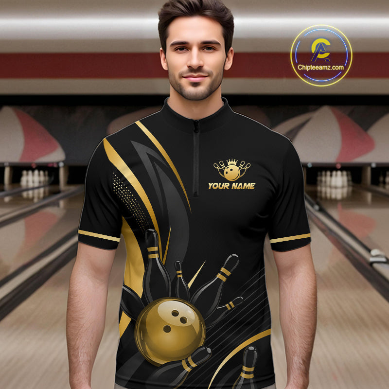 Man wearing a black and gold bowling shirt with a logo and text in a bowling alley.