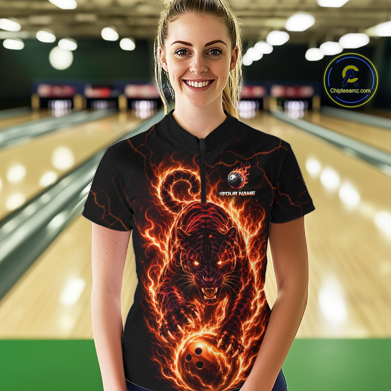 Woman wearing a black bowling shirt with a fiery panther design in a bowling alley.