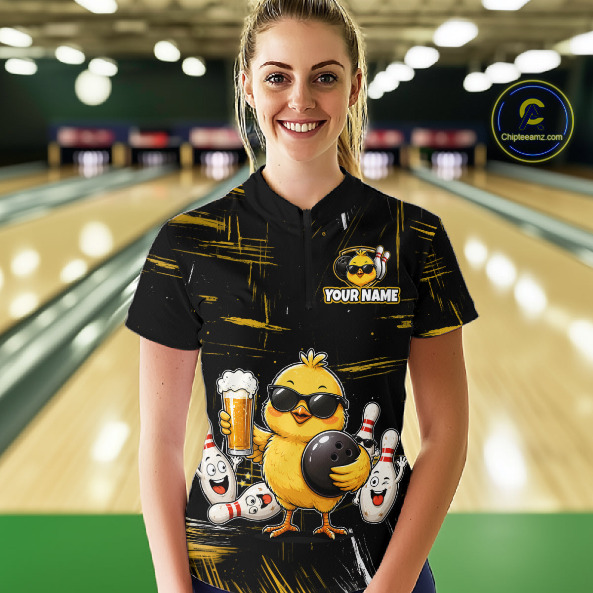 Women wearing bowling quarter zip shirt featuring a chick holding a bowling ball surrounded by smiling pins and beer graphics on black yellow background.