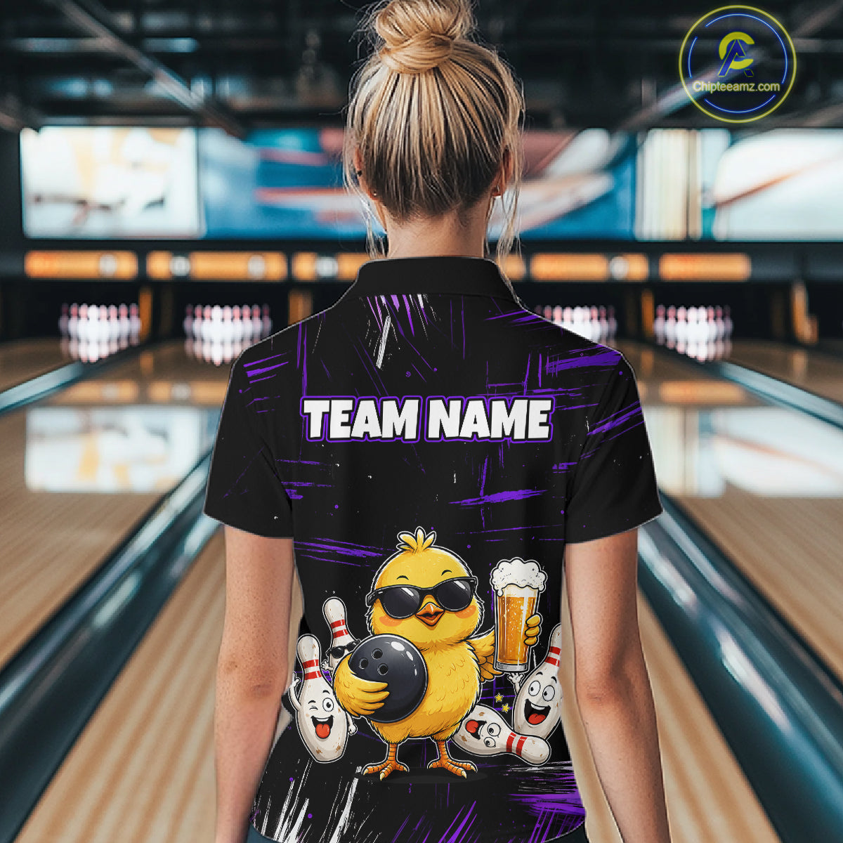 Women wearing bowling quarter zip shirt featuring a chick holding a bowling ball surrounded by smiling pins and beer graphics on black yellow background.