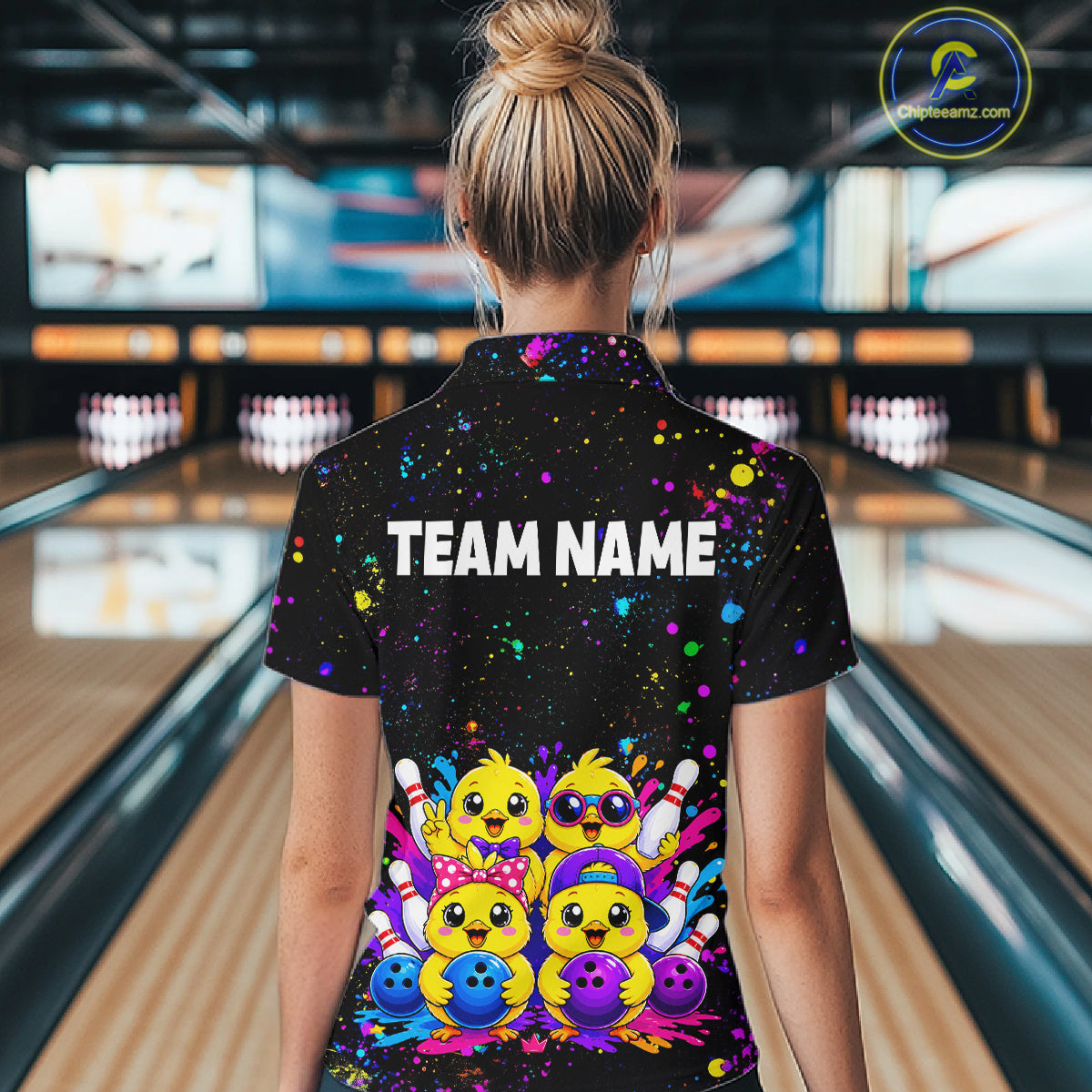 Women wearing personalized bowling quarter zip shirt with cartoon chicks holding bowling balls, framed by pins and colorful paint patterns on a black layout.