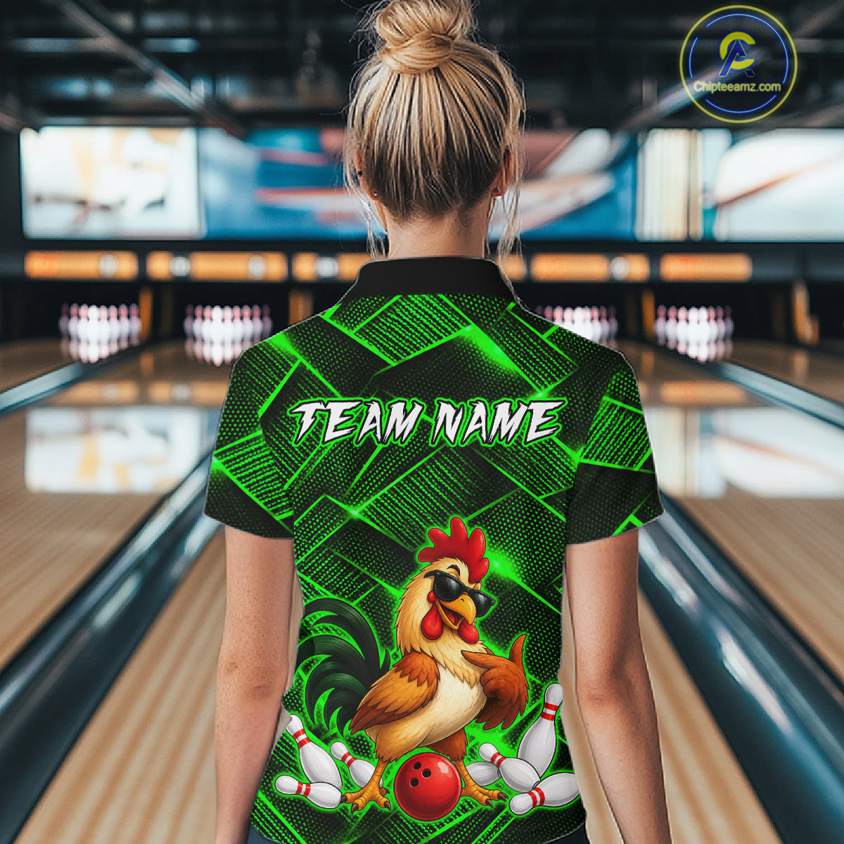Woman wearing a green and black bowling quarter zip shirt featuring a cool rooster mascot wearing sunglasses, a red bowling ball, bowling pins, and custom team name text.