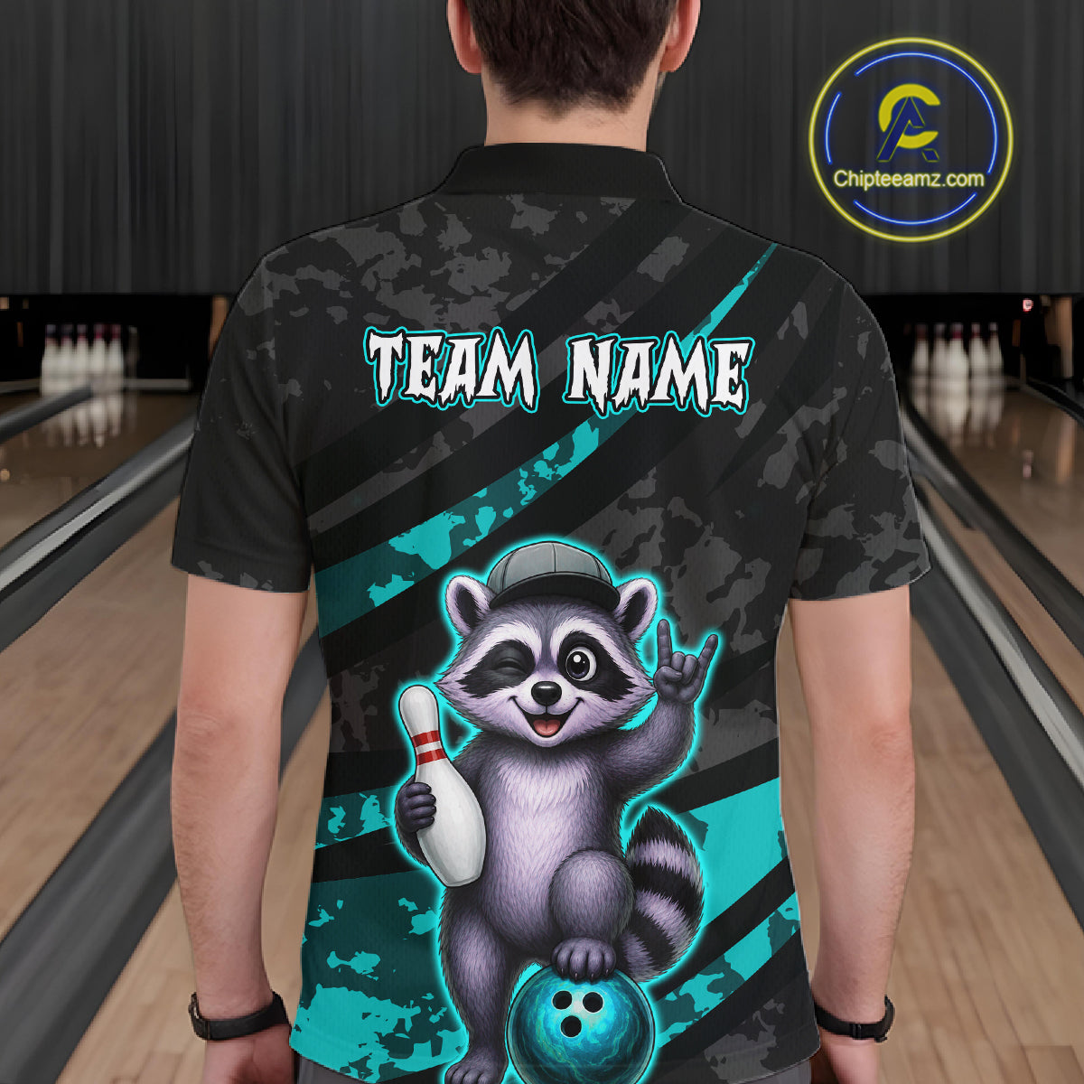 Person wearing a bowling-themed shirt with a raccoon graphic in a bowling alley.