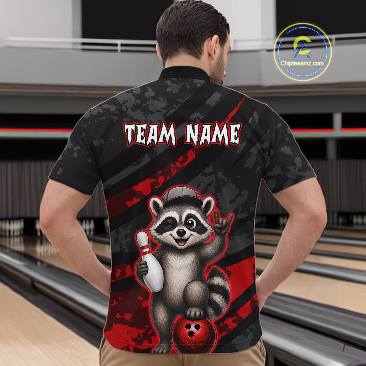 Person wearing a bowling shirt with a raccoon graphic and 'Team Name' text in a bowling alley.