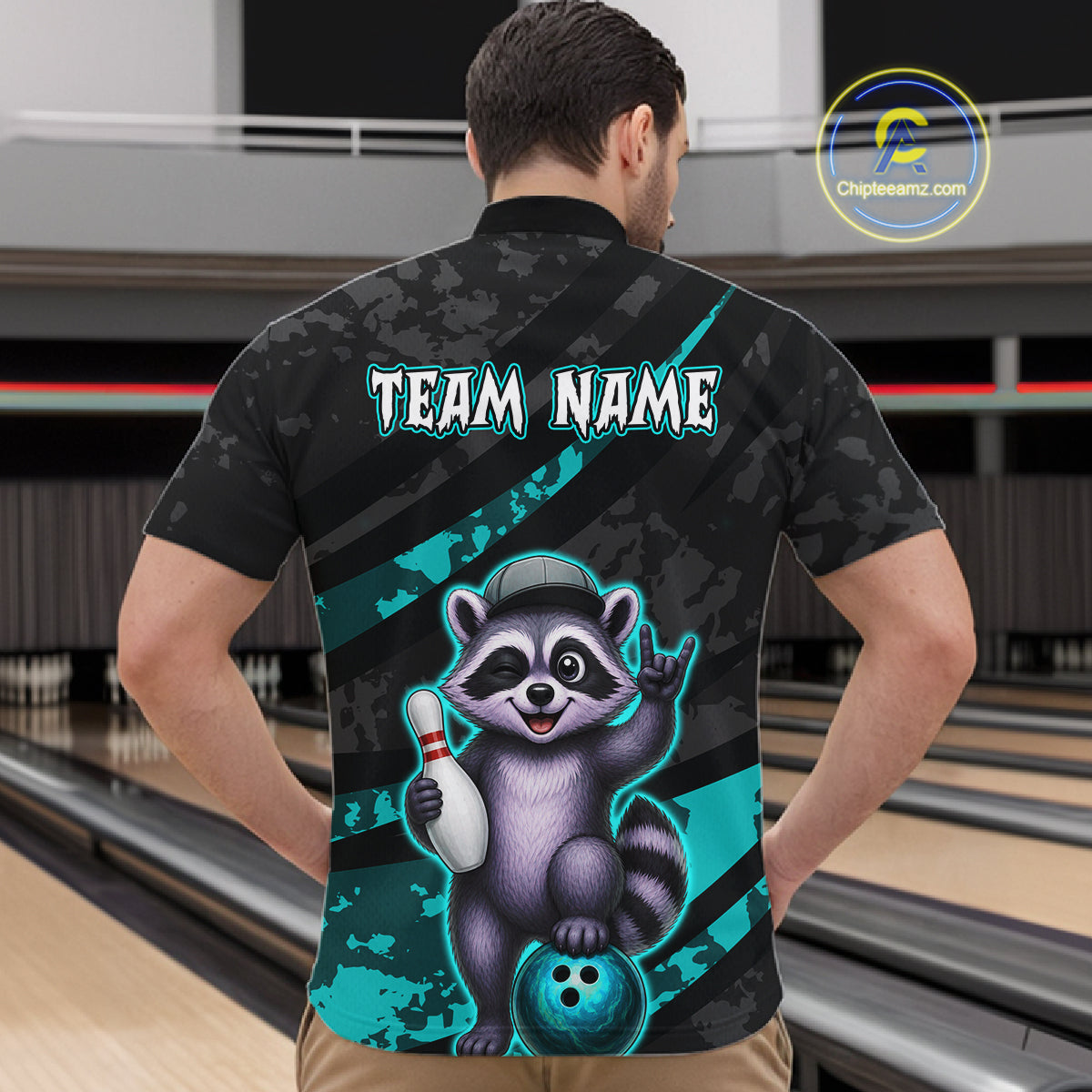 Person wearing a black bowling shirt with a raccoon graphic and 'Team Name' text in a bowling alley.