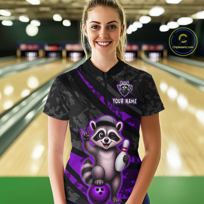 Person wearing a bowling shirt with a raccoon graphic in a bowling alley