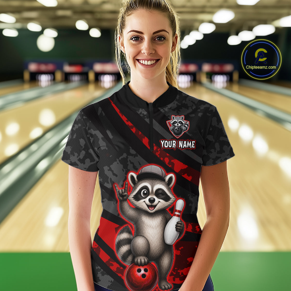 Person wearing a black bowling shirt with a raccoon graphic in a bowling alley.