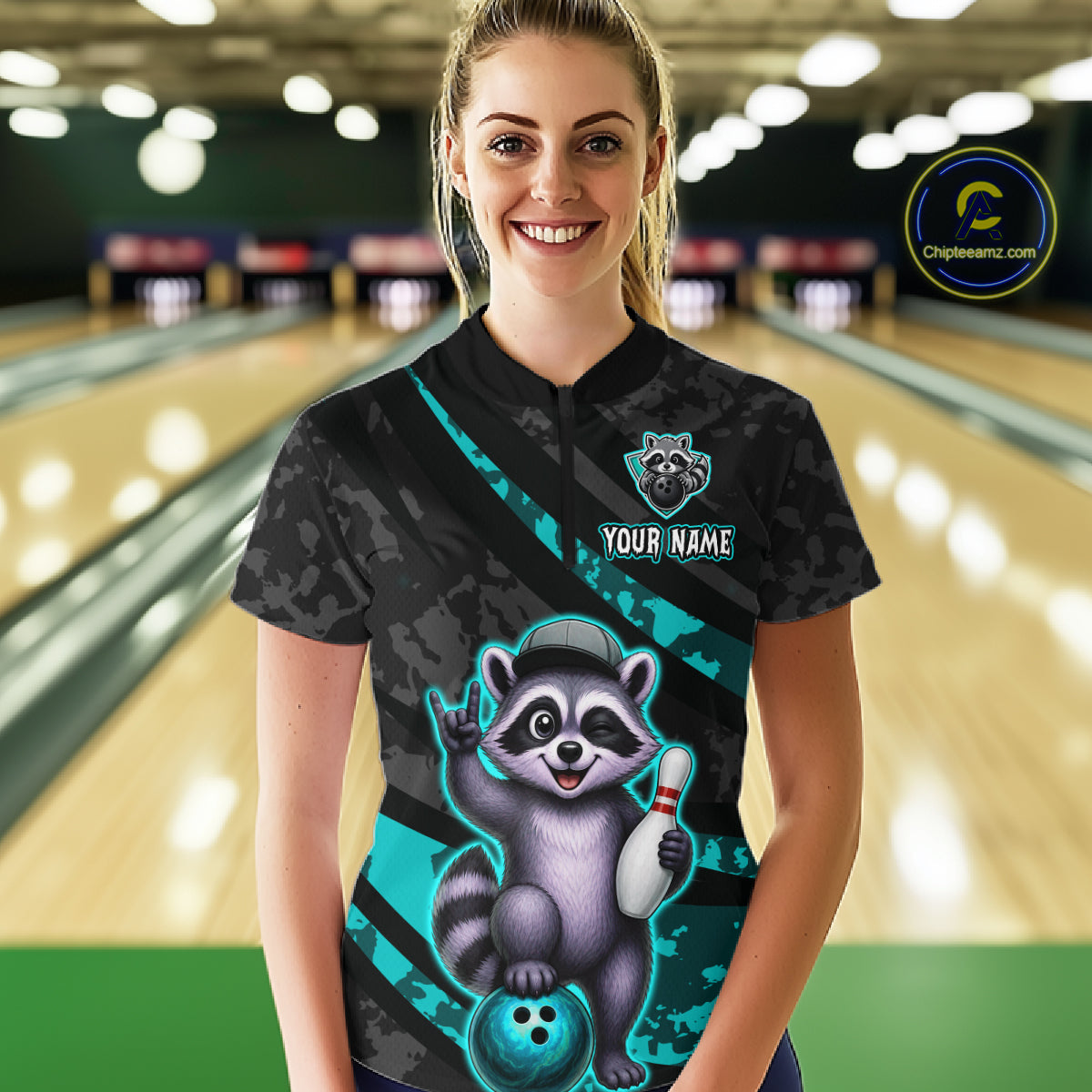 Person wearing a black bowling shirt with a raccoon design in a bowling alley.