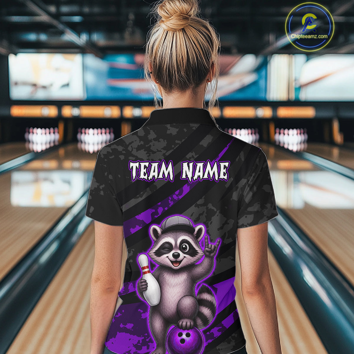 Person wearing a bowling shirt with a raccoon graphic and 'TEAM NAME' text in a bowling alley.