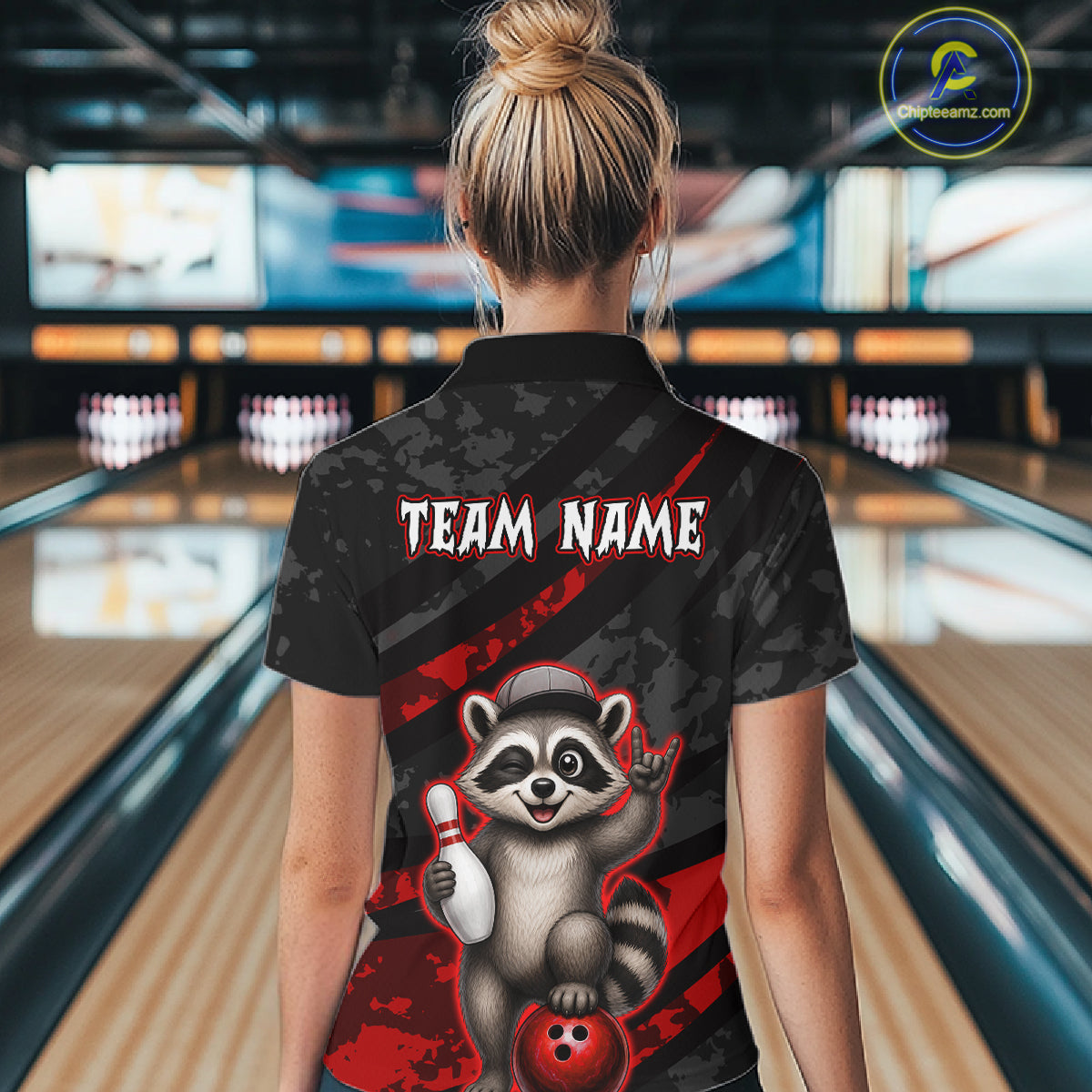 Person wearing a bowling shirt with a raccoon graphic and 'TEAM NAME' text in a bowling alley.
