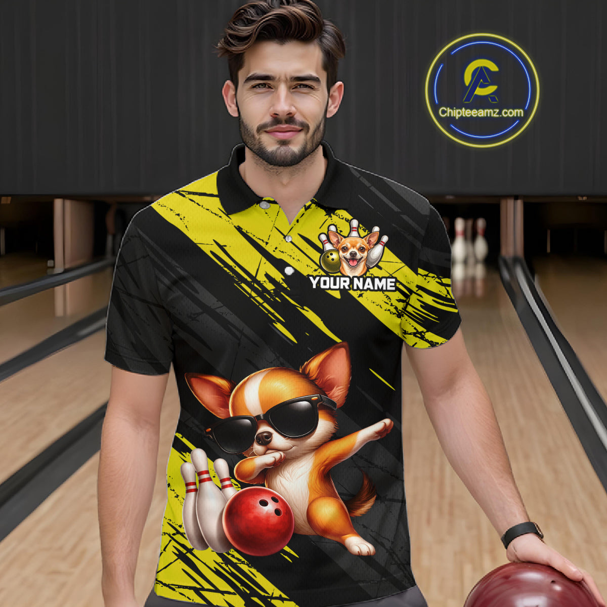 Man wearing a black and yellow polo shirt with a dog graphic holding a bowling ball in a bowling alley.