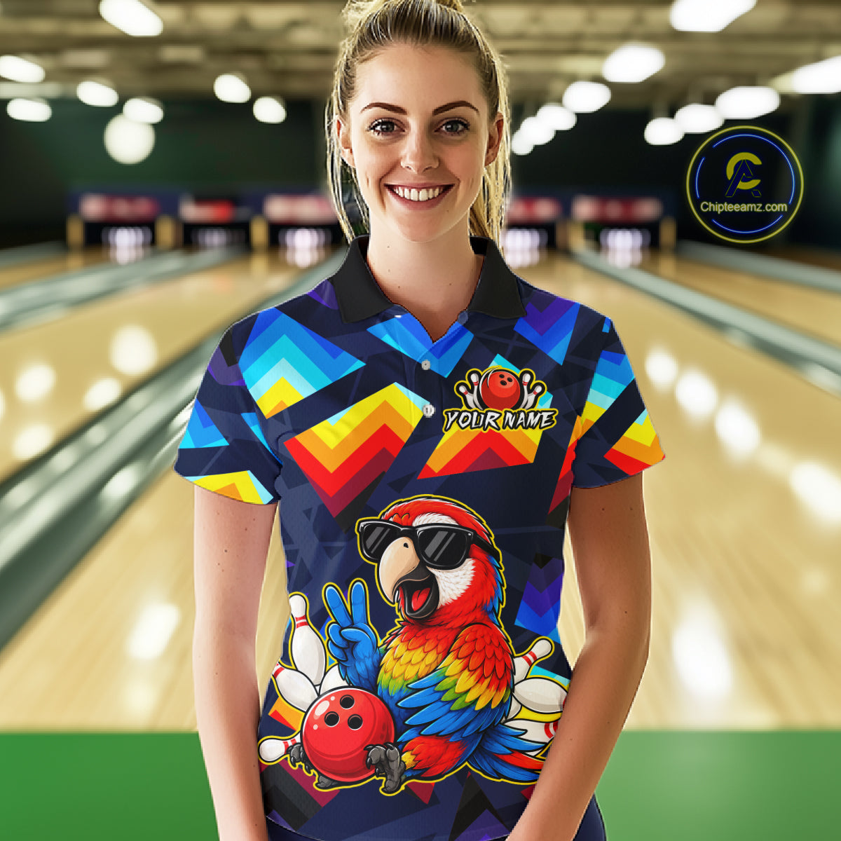 A woman stands in a bowling alley wearing a short-sleeve collared bowling shirt with a colorful geometric pattern and a large parrot graphic on the front. The shirt has a custom name patch on the chest and a circular 'Chippewazinc.