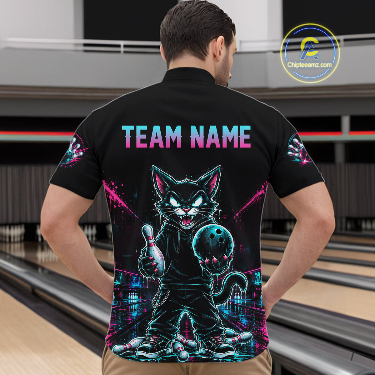 A man viewed from behind wearing a black short-sleeve bowling-themed polo shirt with a large neon cat graphic and the text 'TEAM NAME' on the back. The shirt also has matching graphics on the sleeves.