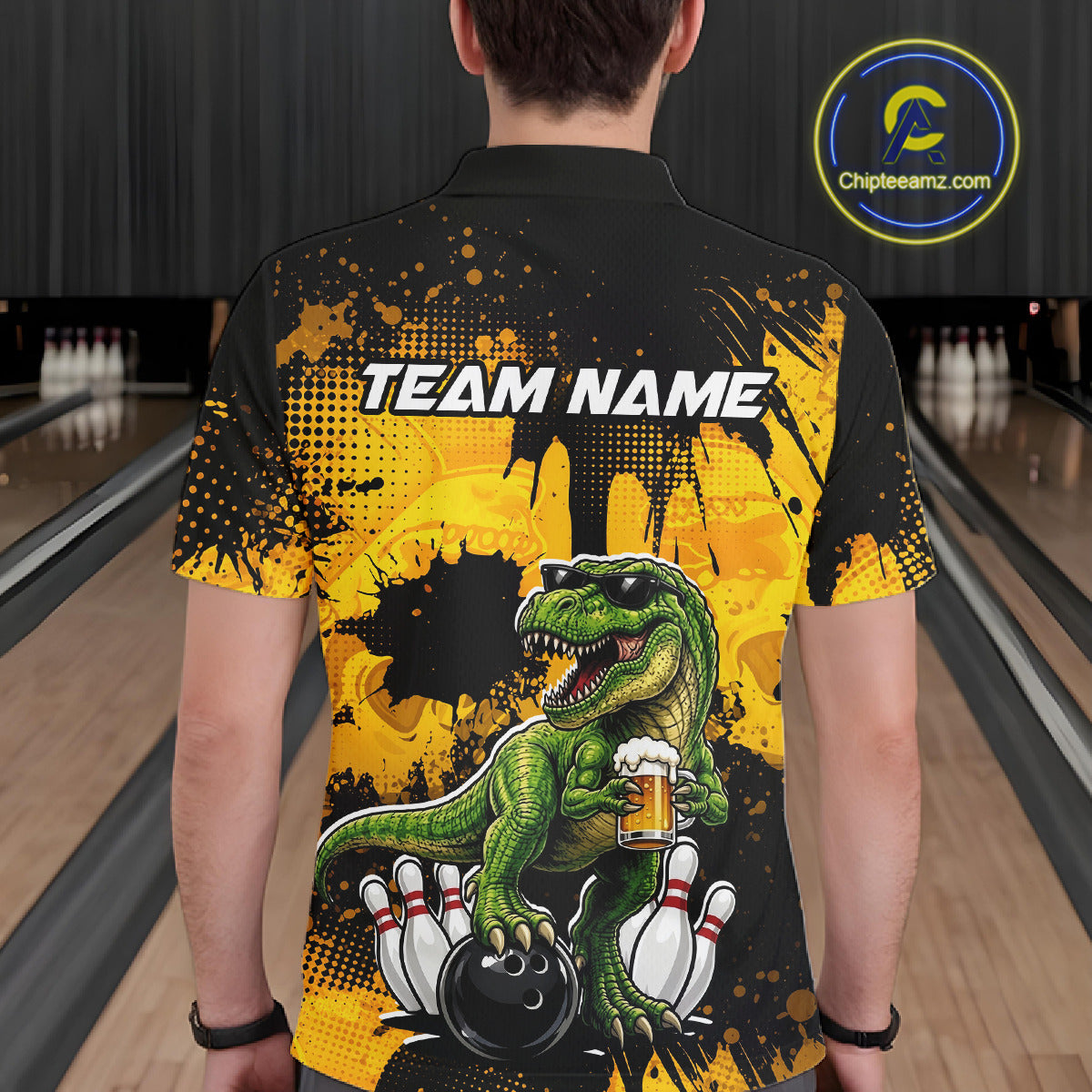 Man wearing a black bowling polo featuring a green T-Rex wearing sunglasses, holding a beer mug, standing with bowling pins and a bowling ball, plus personalized name and team name text.