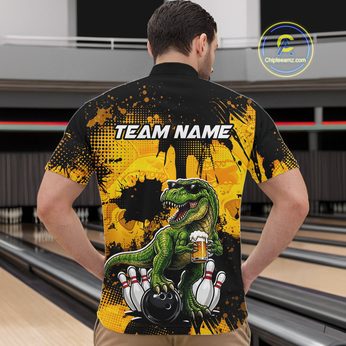 Man wearing a black bowling quarter zip featuring a green T-Rex wearing sunglasses, holding a beer mug, standing with bowling pins and a bowling ball, plus personalized name and team name text.