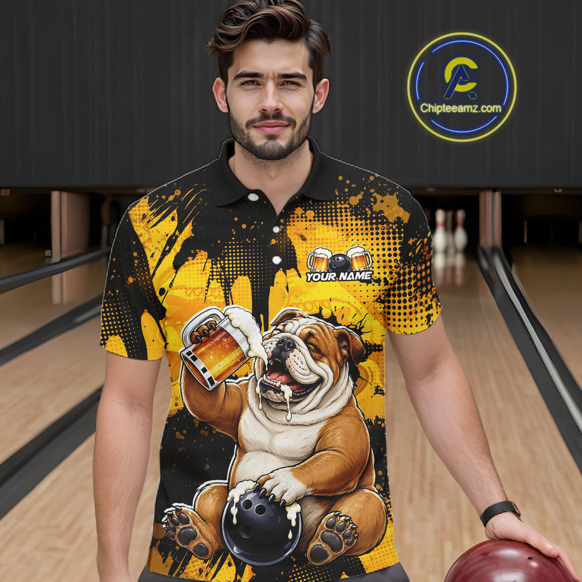 Man wearing a black and yellow polo shirt with a bulldog graphic in a bowling alley.