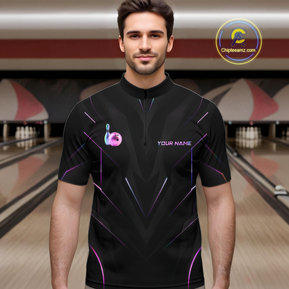 Man wearing a black bowling shirt with a logo and text in a bowling alley.
