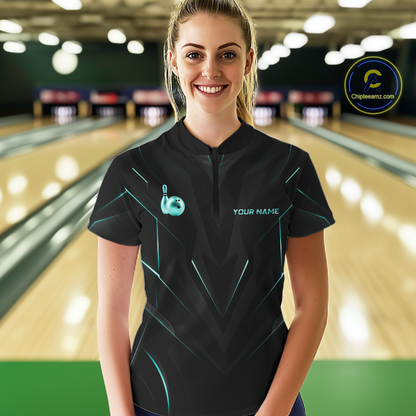 Woman wearing a black bowling shirt with teal accents in a bowling alley.