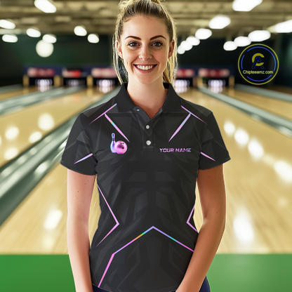 Woman wearing a black bowling shirt with colorful designs in a bowling alley.