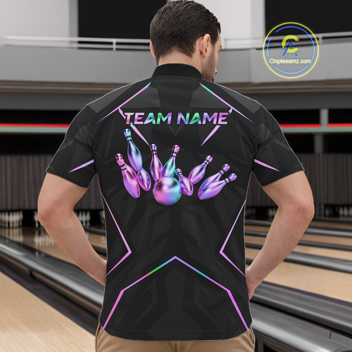 Person wearing a black bowling shirt with colorful designs and 'TEAM NAME' text in a bowling alley.