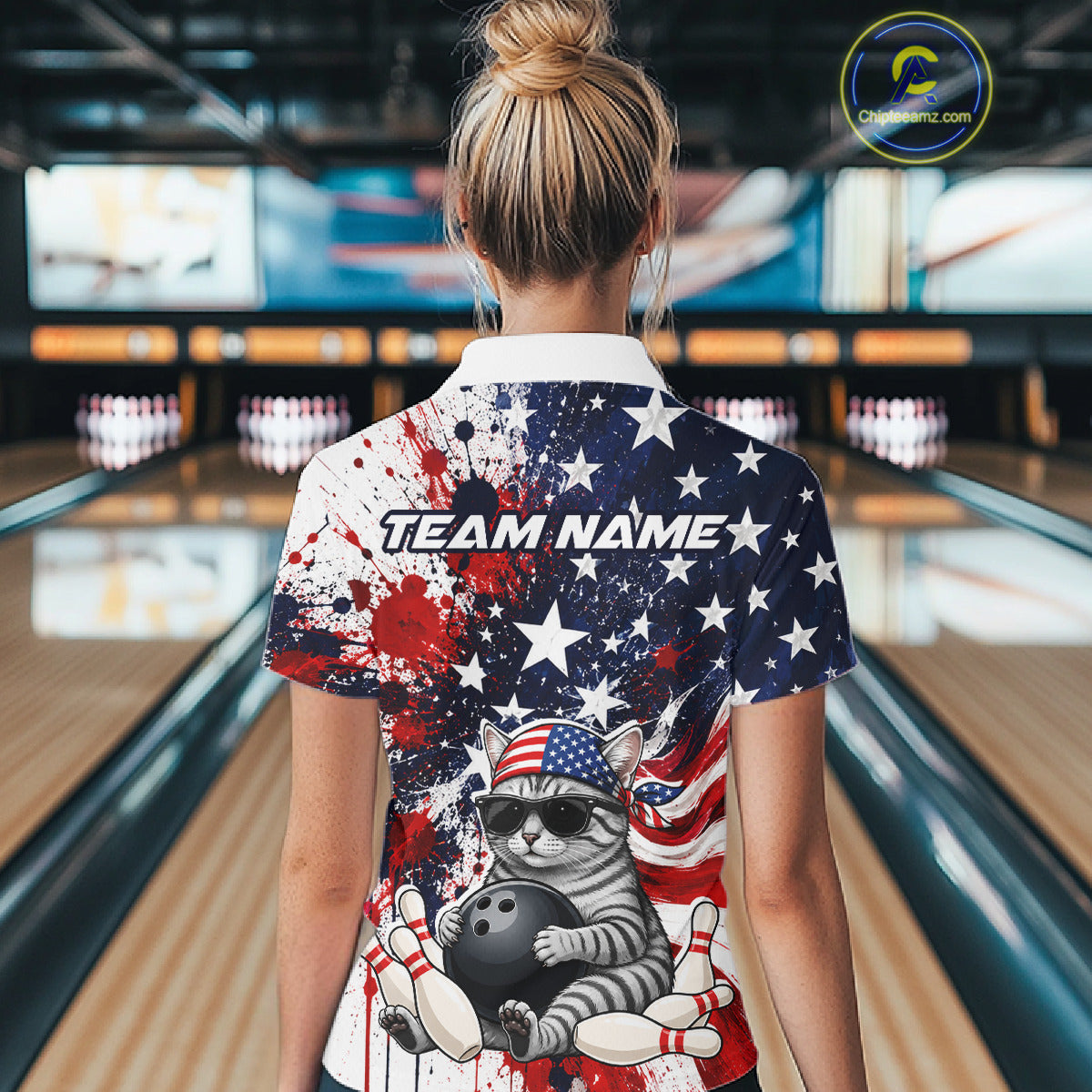 Person wearing a colorful bowling shirt with a cat design and 'Team Name' text in a bowling alley.