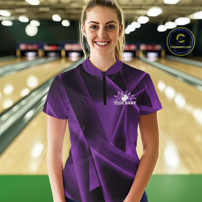 Person wearing a purple bowling shirt with a logo and text in a bowling alley.