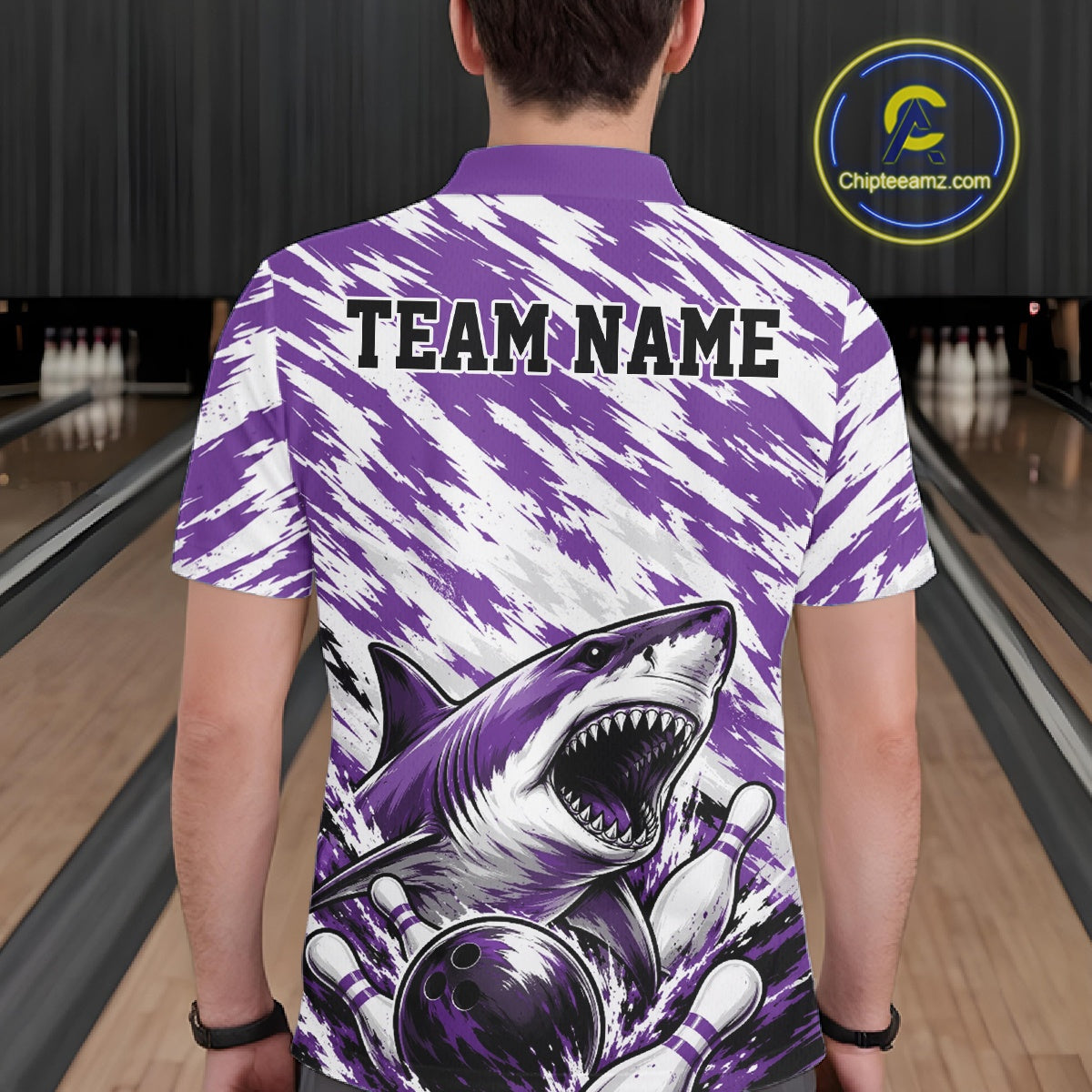 Person wearing a purple and white bowling shirt with a shark graphic and 'TEAM NAME' text at a bowling alley.
