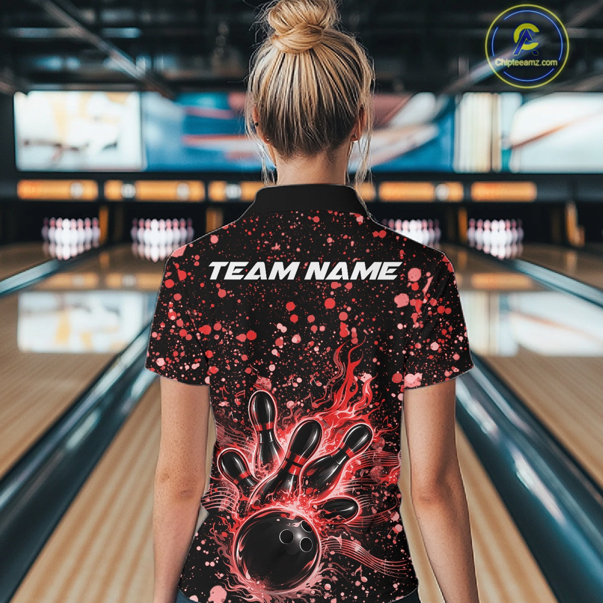 Back view of a female model in a black bowling quarter-zip shirt displaying fiery bowling artwork with red splatter accents.