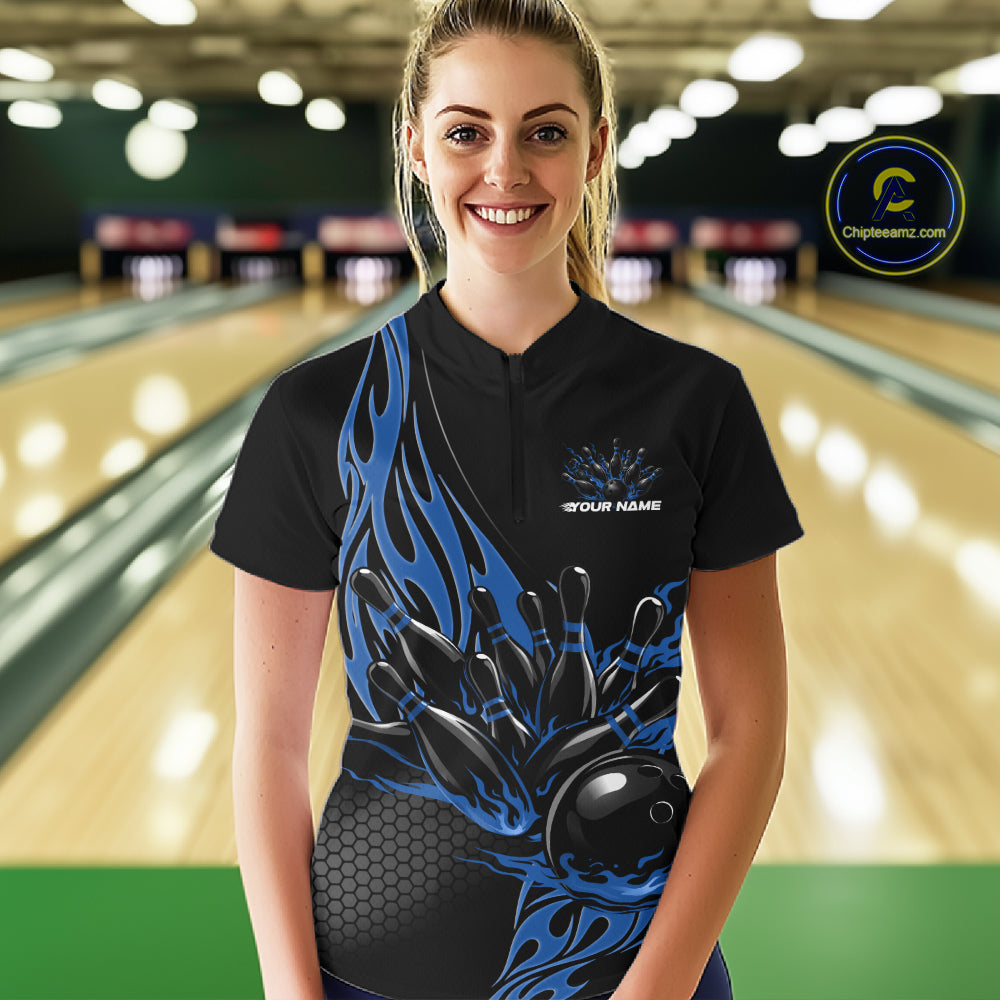 Female model front view in bowling alley wearing black quarter zip shirt with blue flame bowling ball hitting pins illustration
