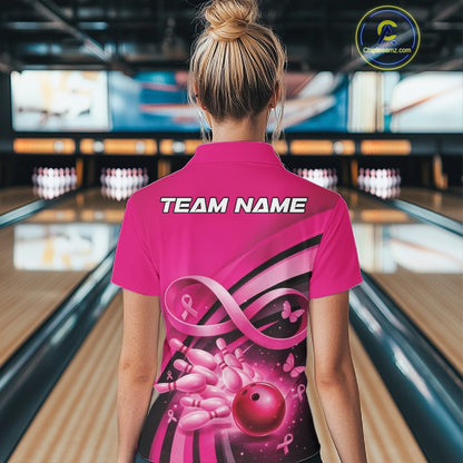 Back view of a women s pink bowling quarter zip showcasing breast cancer awareness ribbons, butterfly accents, and bowling artwork inside a bowling alley.