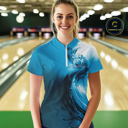Woman wearing a blue bowling shirt with a design in a bowling alley