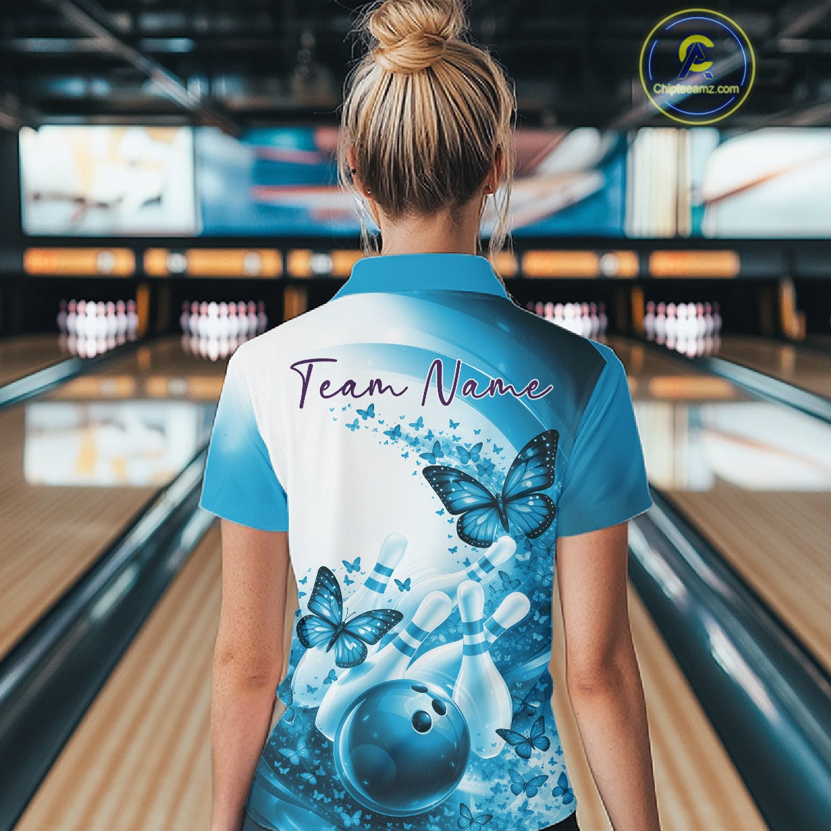 Back view of a female model wearing a blue bowling quarter zip with butterfly graphics and bowling-themed artwork