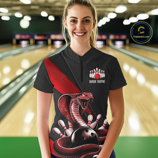 Female model wearing a black bowling quarter-zip in a bowling alley with red cobra artwork and bowling-themed graphics.