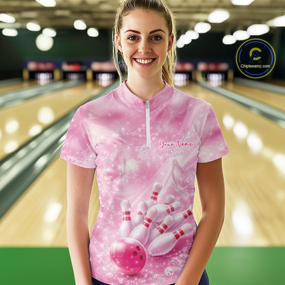 Female model in a bowling lane wearing a pink quarter zip shirt with butterfly and diamond sparkle bowling graphics.