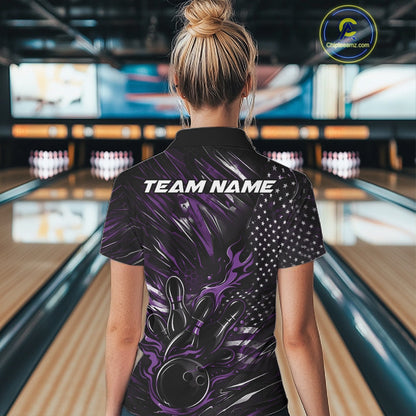 Female model at a bowling lane, back view of black and purple quarter zip shirt showcasing patriotic flames bowling ball hitting pins with American flag accents