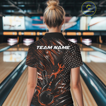 Female model in a bowling lane wearing a black and orange quarter zip shirt, back view featuring patriotic flames bowling ball striking pins with American flag inspired design